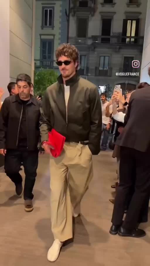 Jacob Elordi wearing a dark bomber, white layer and wide beige trousers at Fashion Week